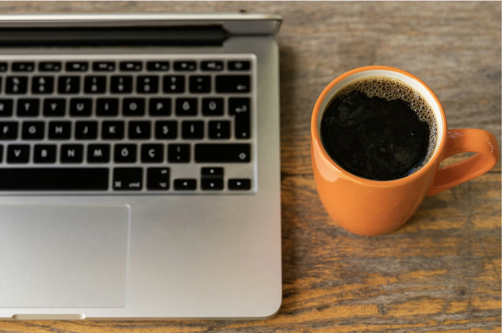 Laptop on desk next to a coffee up