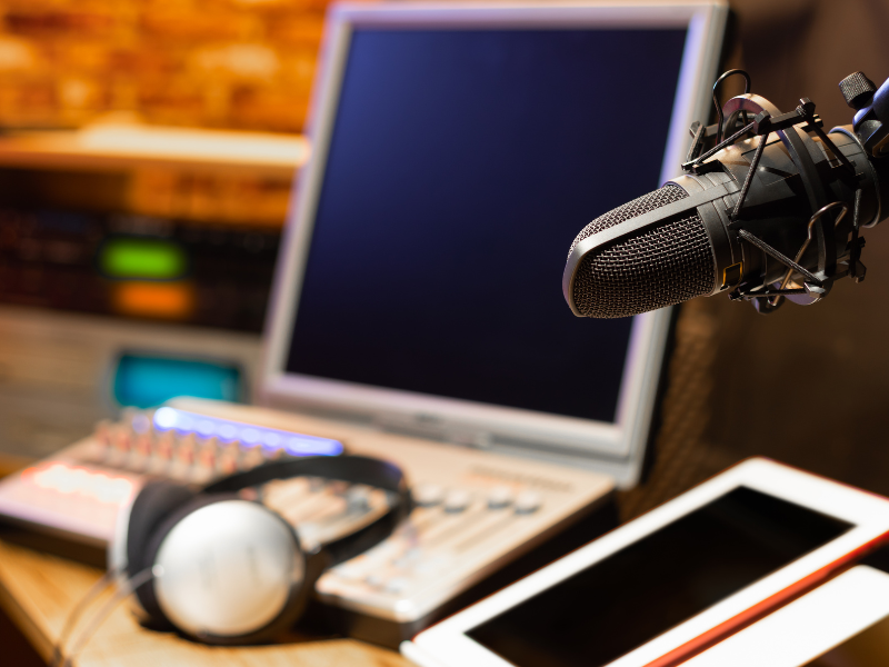 A podcast-style recording setup with a microphone and laptop on a desk, representing the connection between broadcast journalism and online course design.